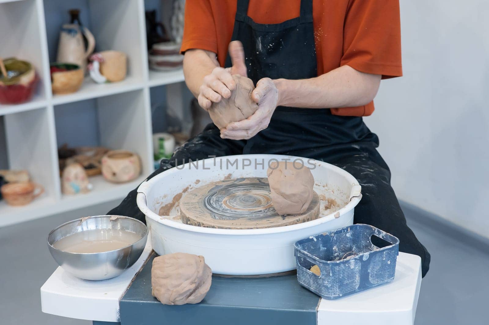 The potter kneads the clay before using it on the potter's wheel. Close-up of a man's hands