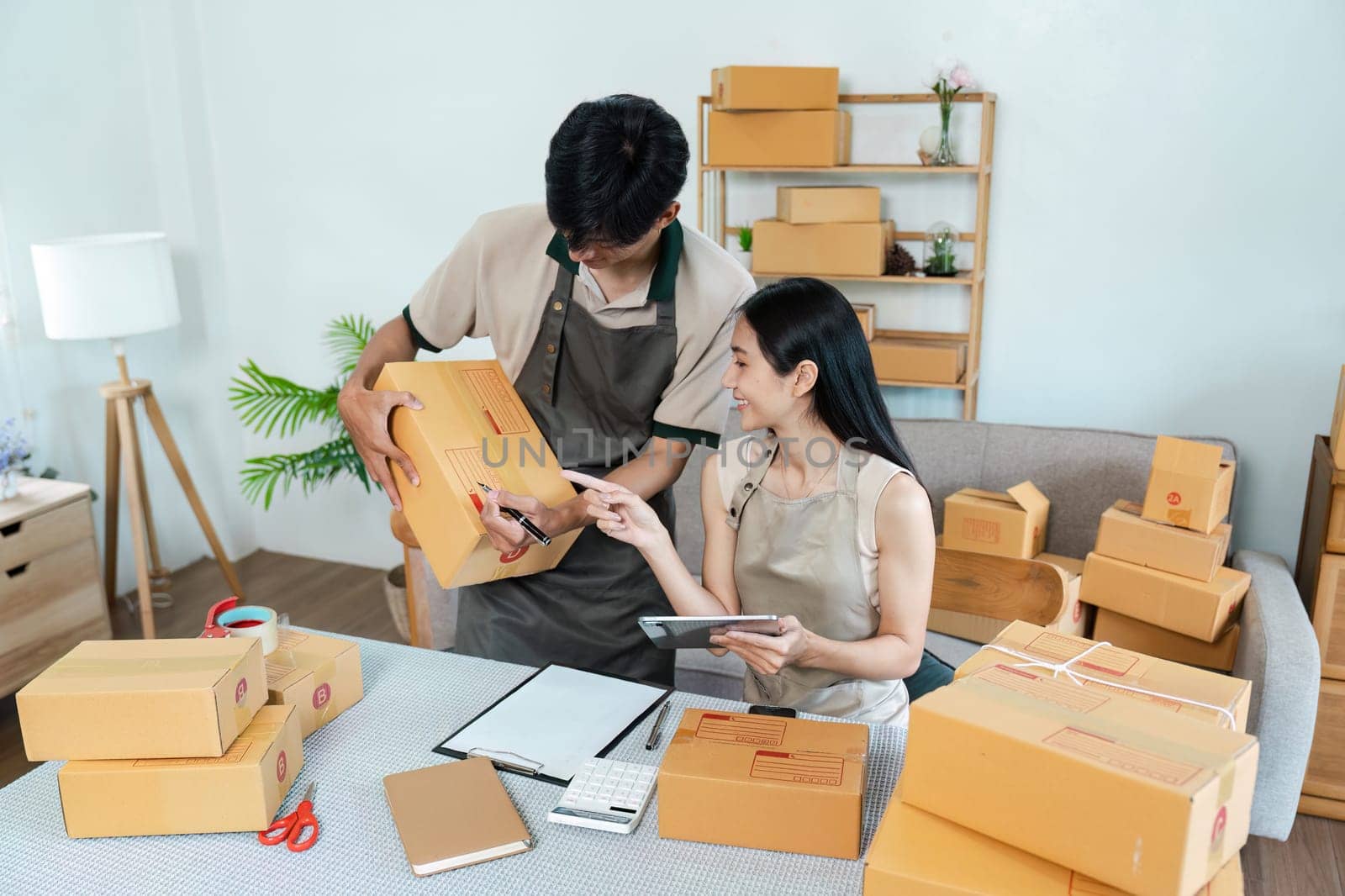 Young entrepreneurs working on their e-business, managing orders and packaging products in a home office setting.