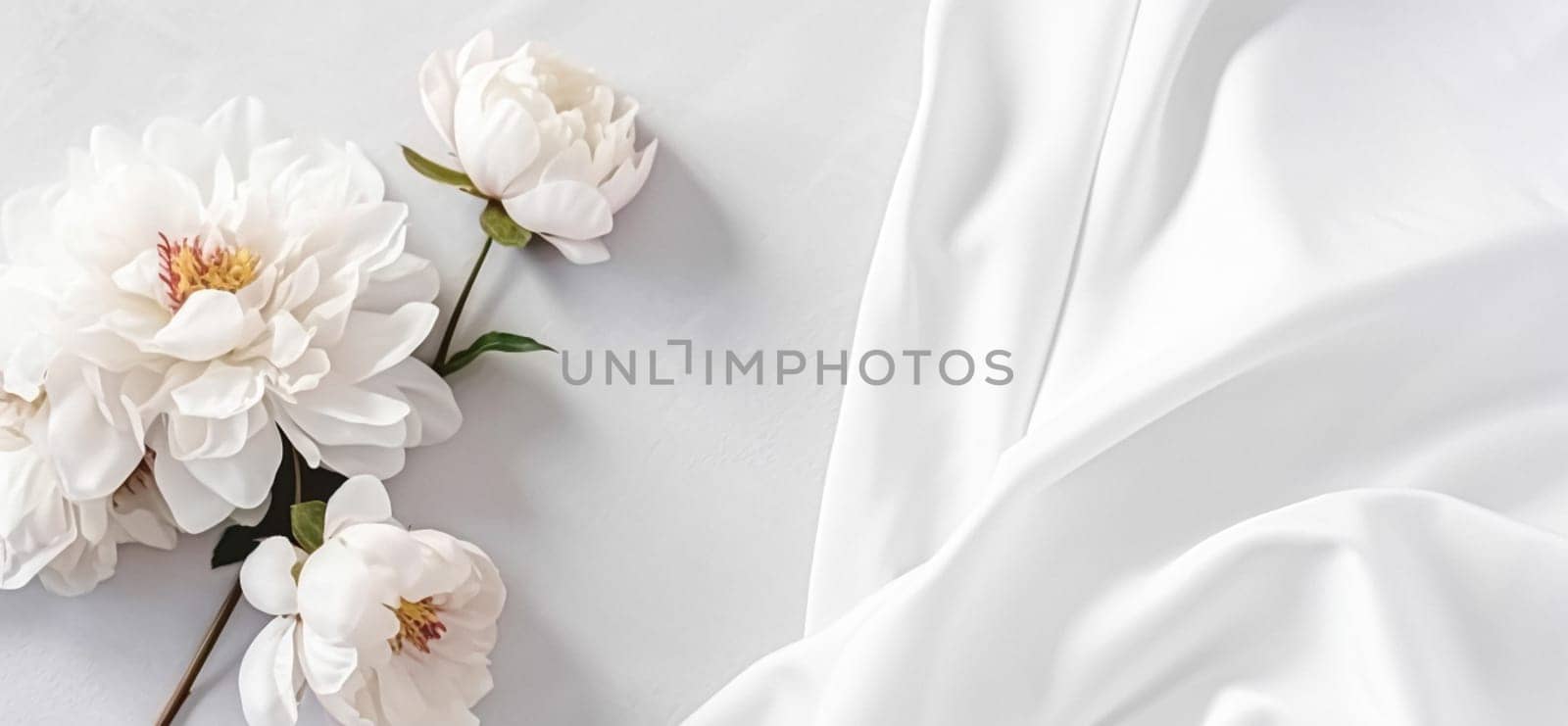 Floral composition. White flowers on white fabric. Flat lay, top view, copy space.