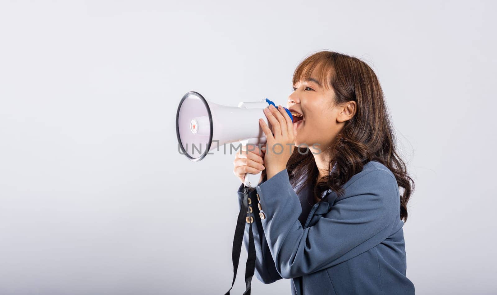 Portrait of happy Asian beautiful young businesswoman confident smiling face holding making announcement message shouting screaming in megaphone, studio shot isolated white background, with copy space