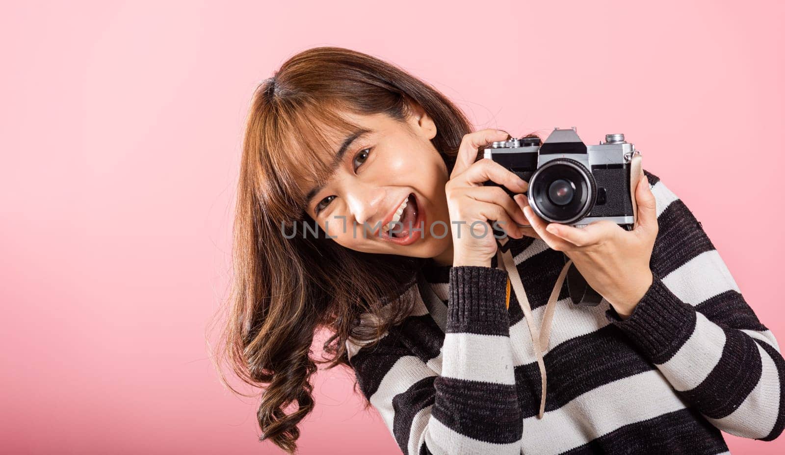 Attractive energetic happy Asian portrait beautiful young woman smiling photographer taking a picture and looking viewfinder on retro vintage photo camera ready to shoot isolated by Sorapop