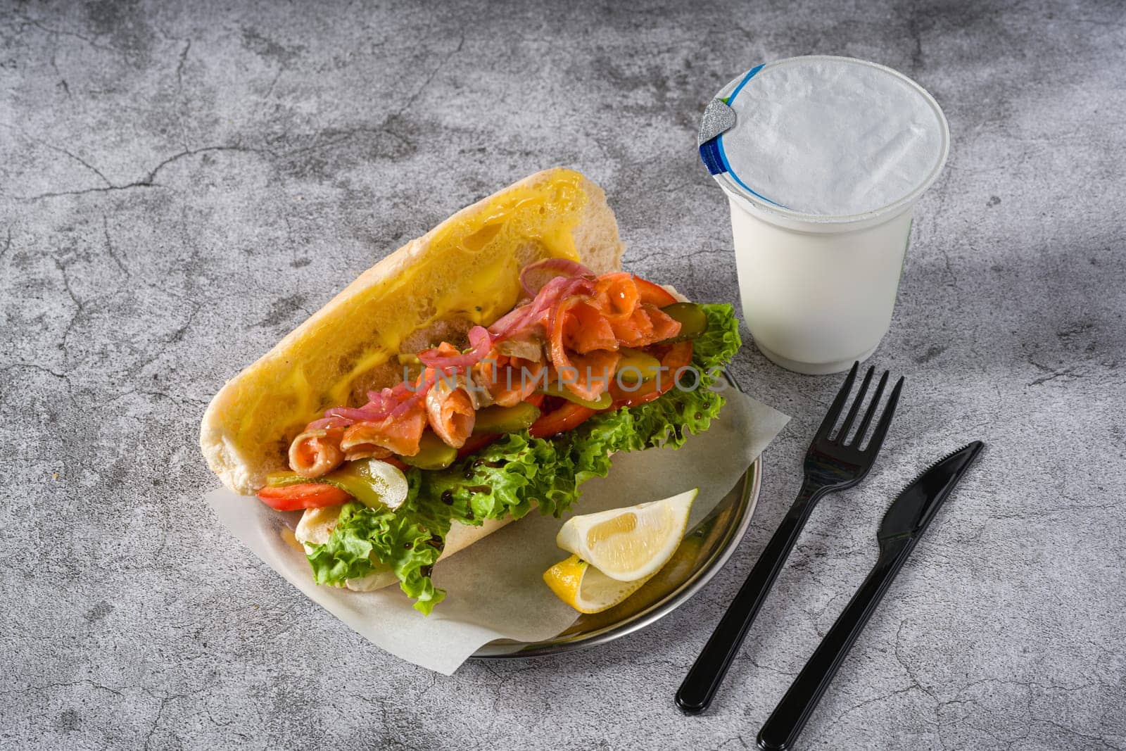 Smoked salmon sandwich on metal plate on stone table