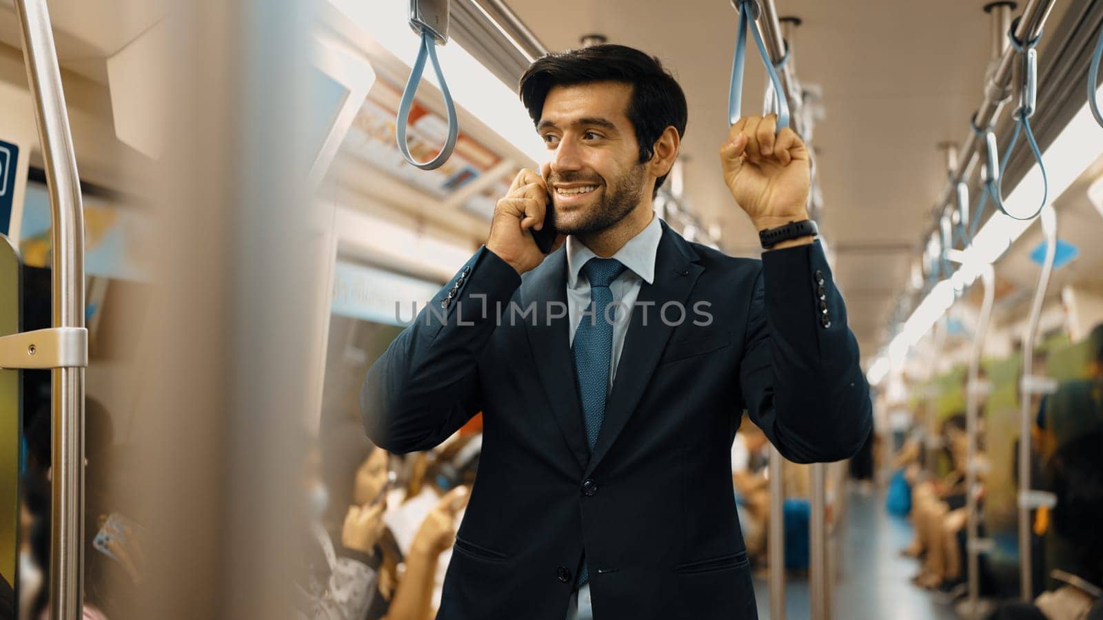 Smart business man phone calling to project manager while standing in train. Professional male leader talking to investor about marketing plan by using phone with blurring background. Exultant.