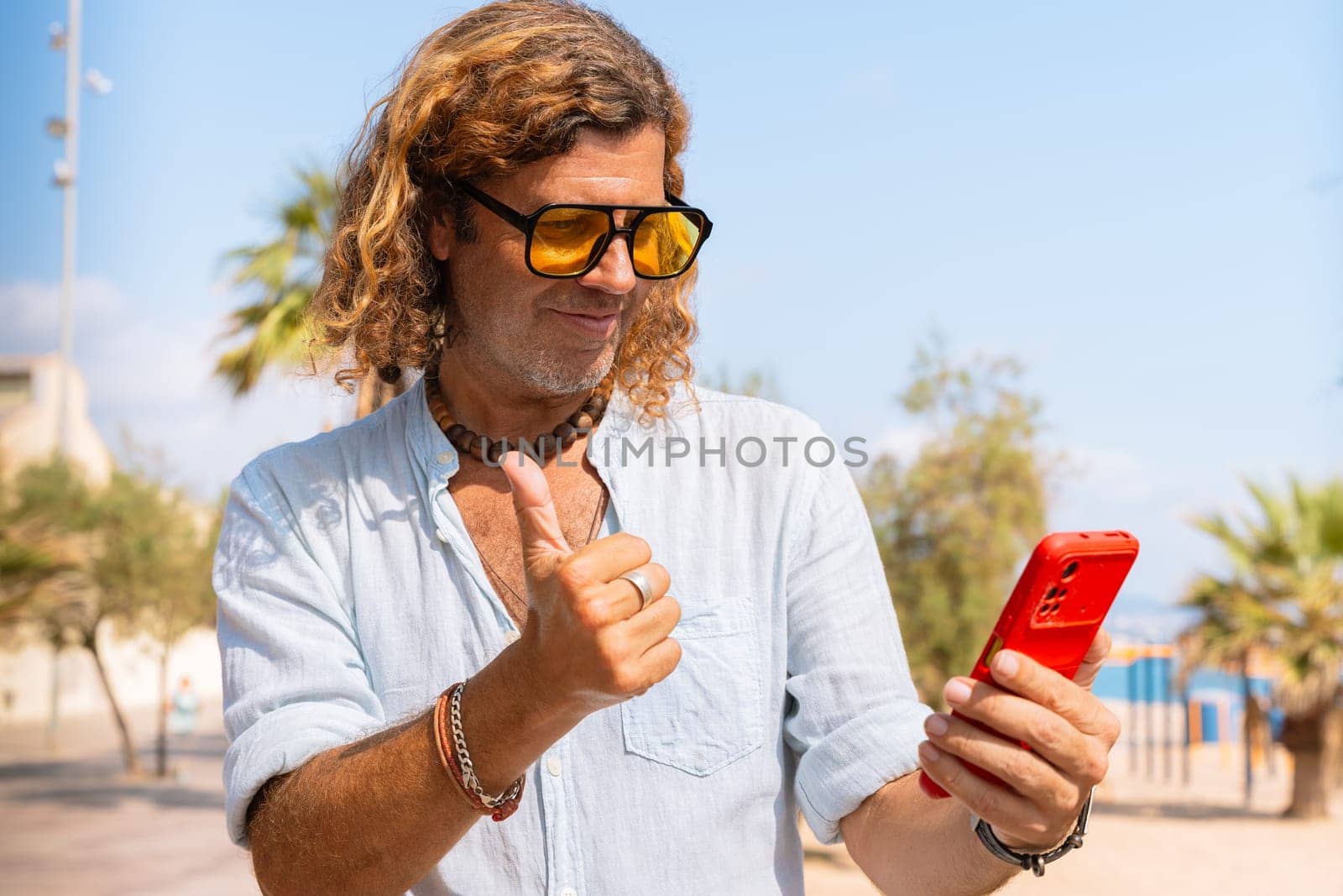 Caucasian man wearing sunglasses feeling smiling showing his finger up in approval outdoors.