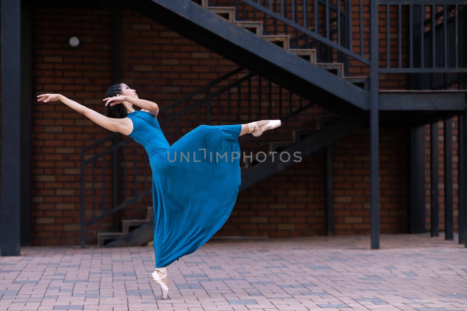 Beautiful Asian ballerina dancing outdoors. Urban landscape