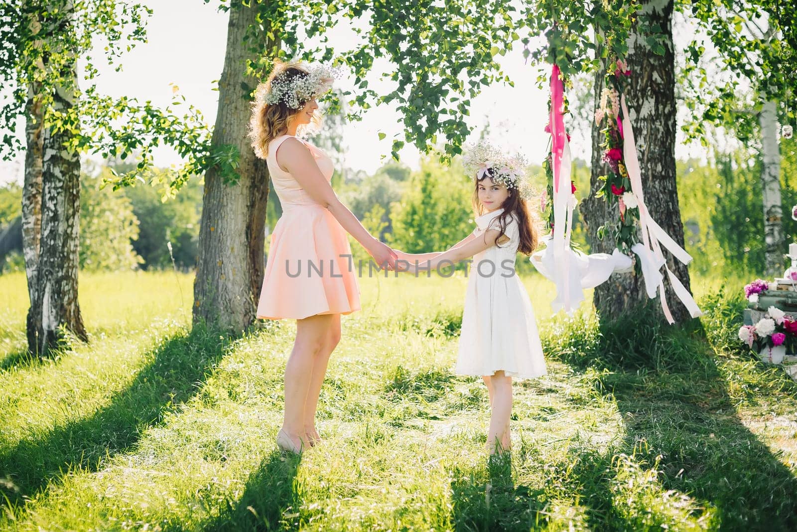 happy mother and daughter holding hands in the summer outdoors