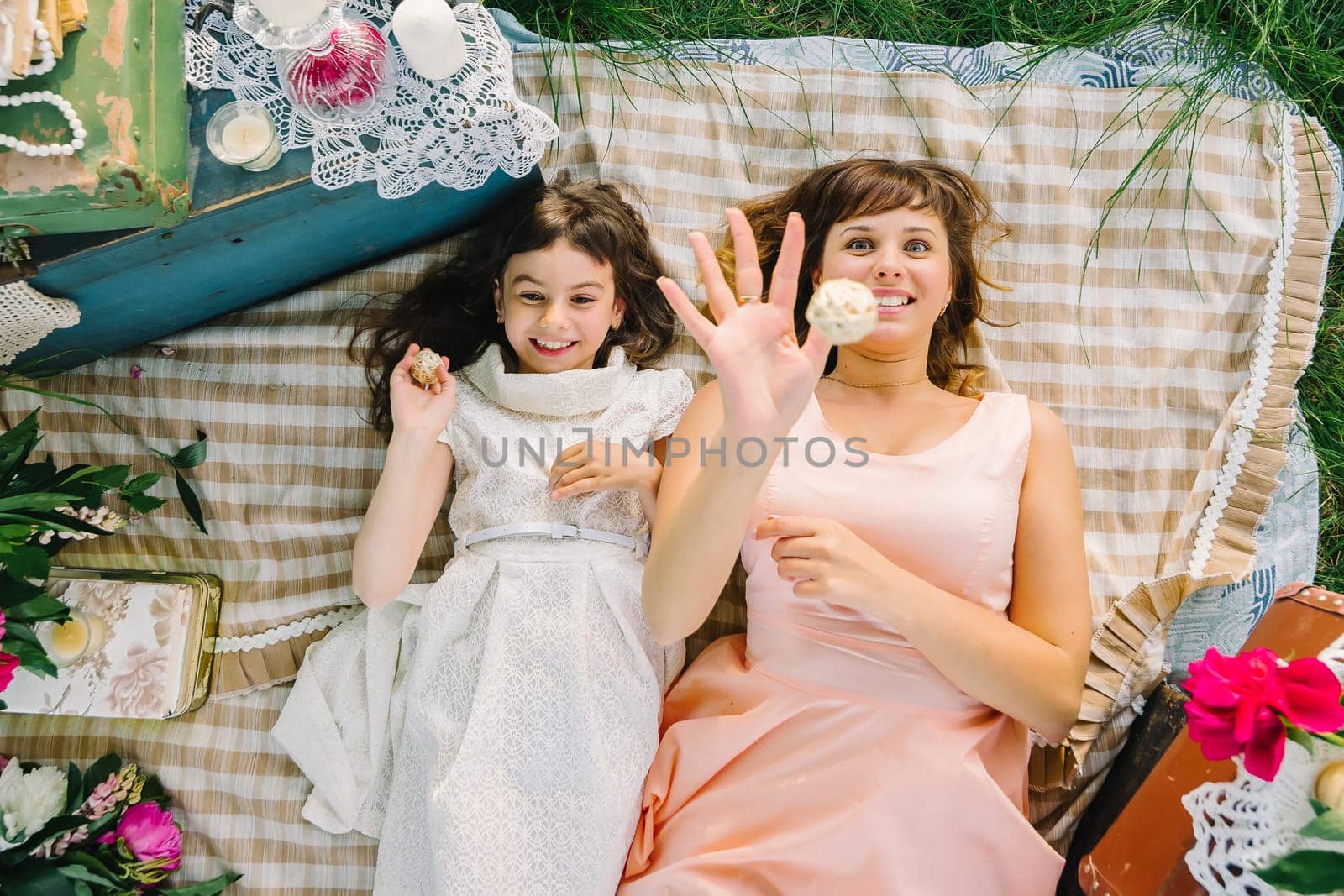 happy mother and daughter playing and smiling while lying on a blanket in the Park in the summer