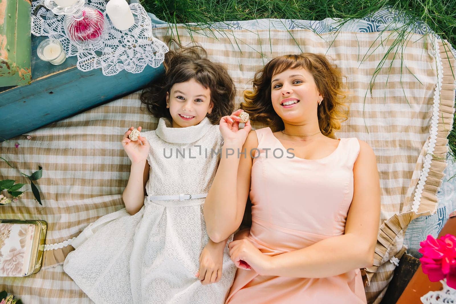 happy mother and daughter playing and smiling while lying on a blanket in the Park in the summer