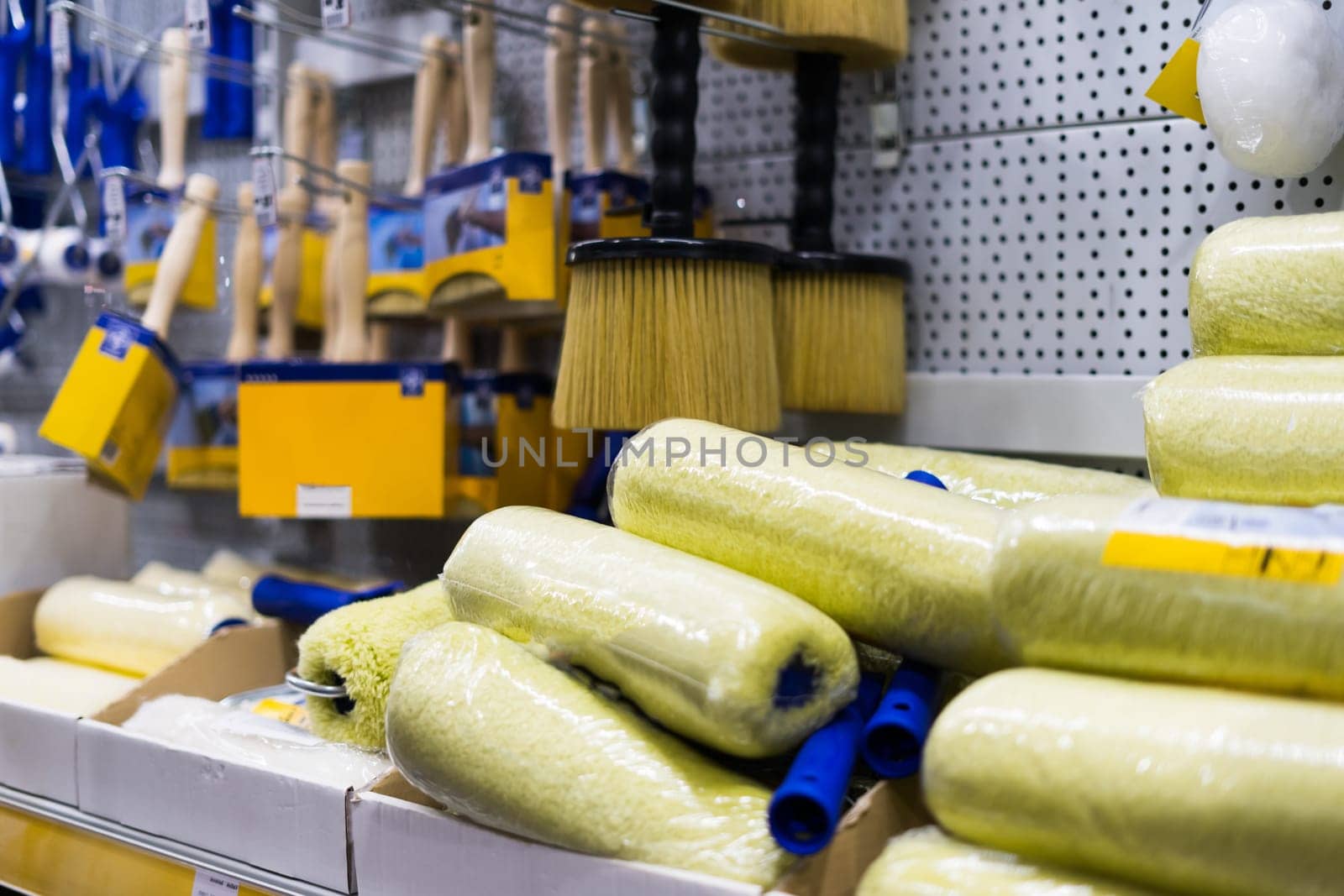 A store display of a paint brushes and rollers. The display is organized by color and size.