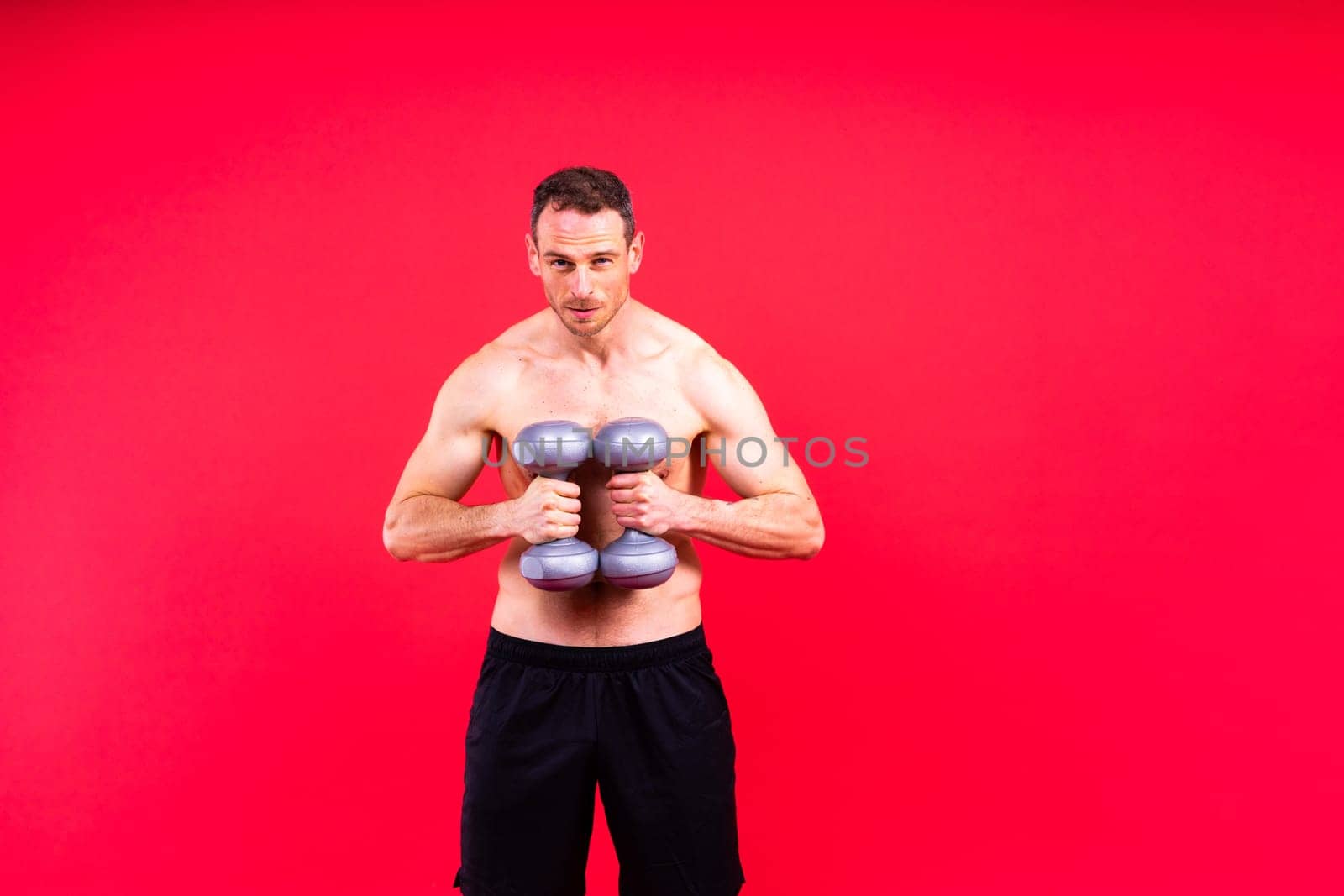 Adult muscular man smiling and screaming while working out hard with dumbbells. by Zelenin