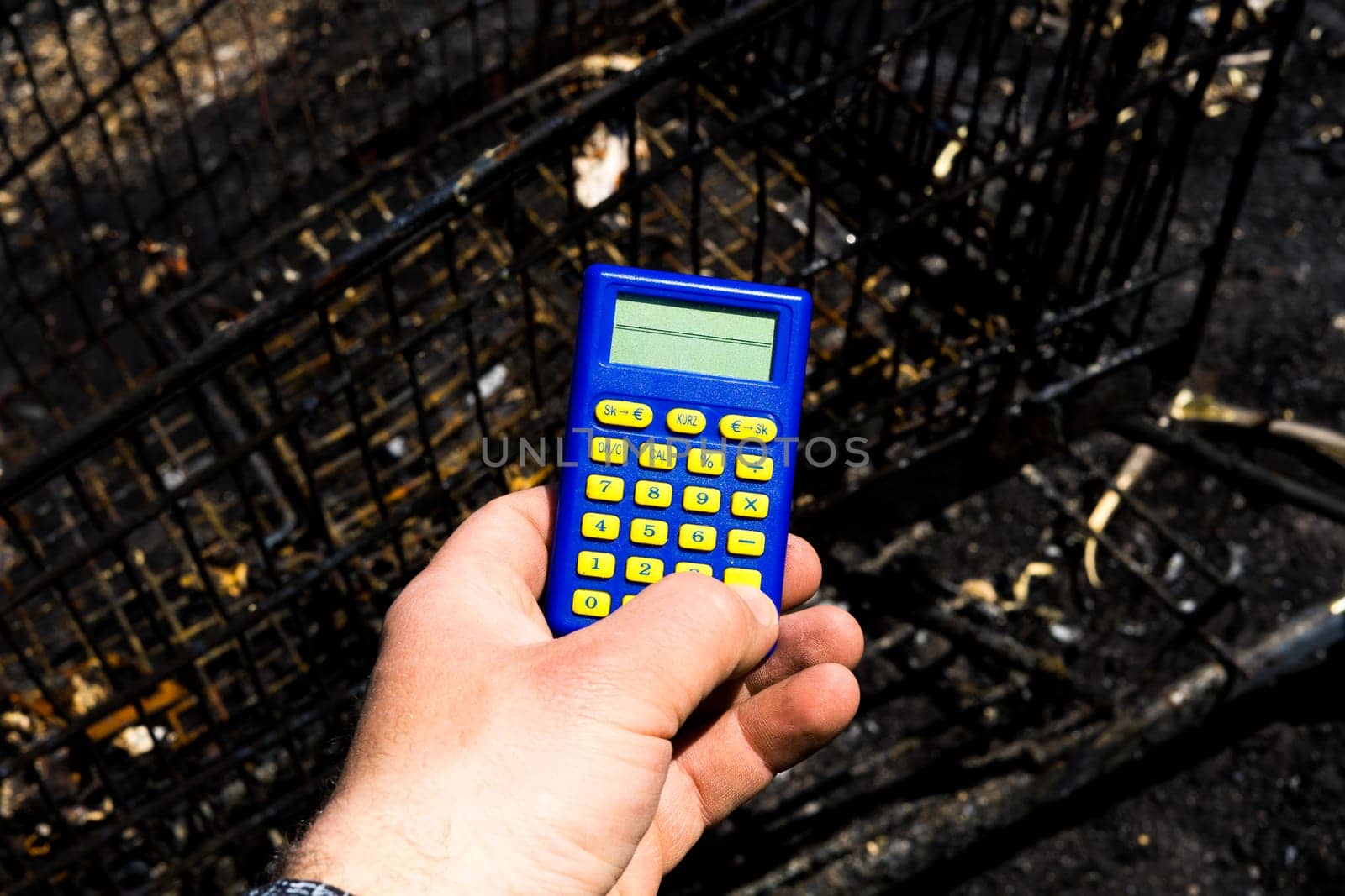 Blue calculator in dark soil, burnt ground after a fire