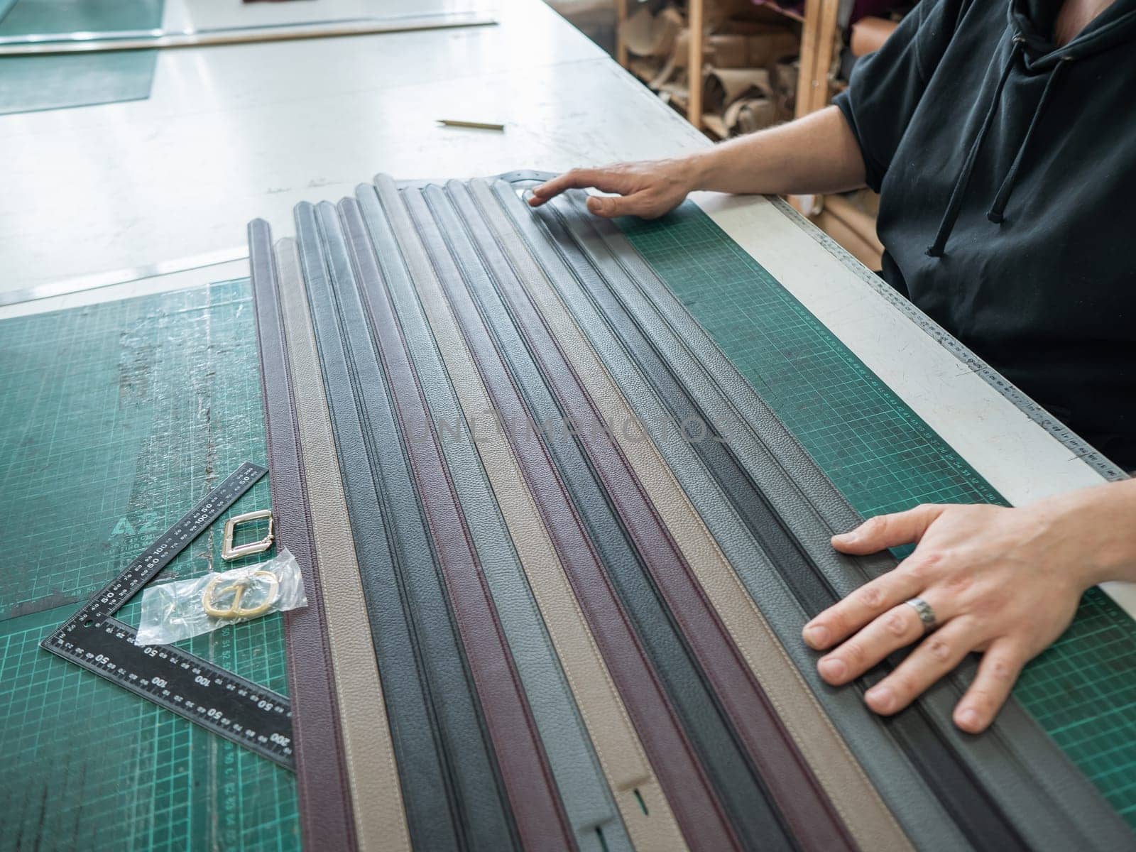 A tanner makes leather belts in a workshop. Close-up of a man's hands. by mrwed54