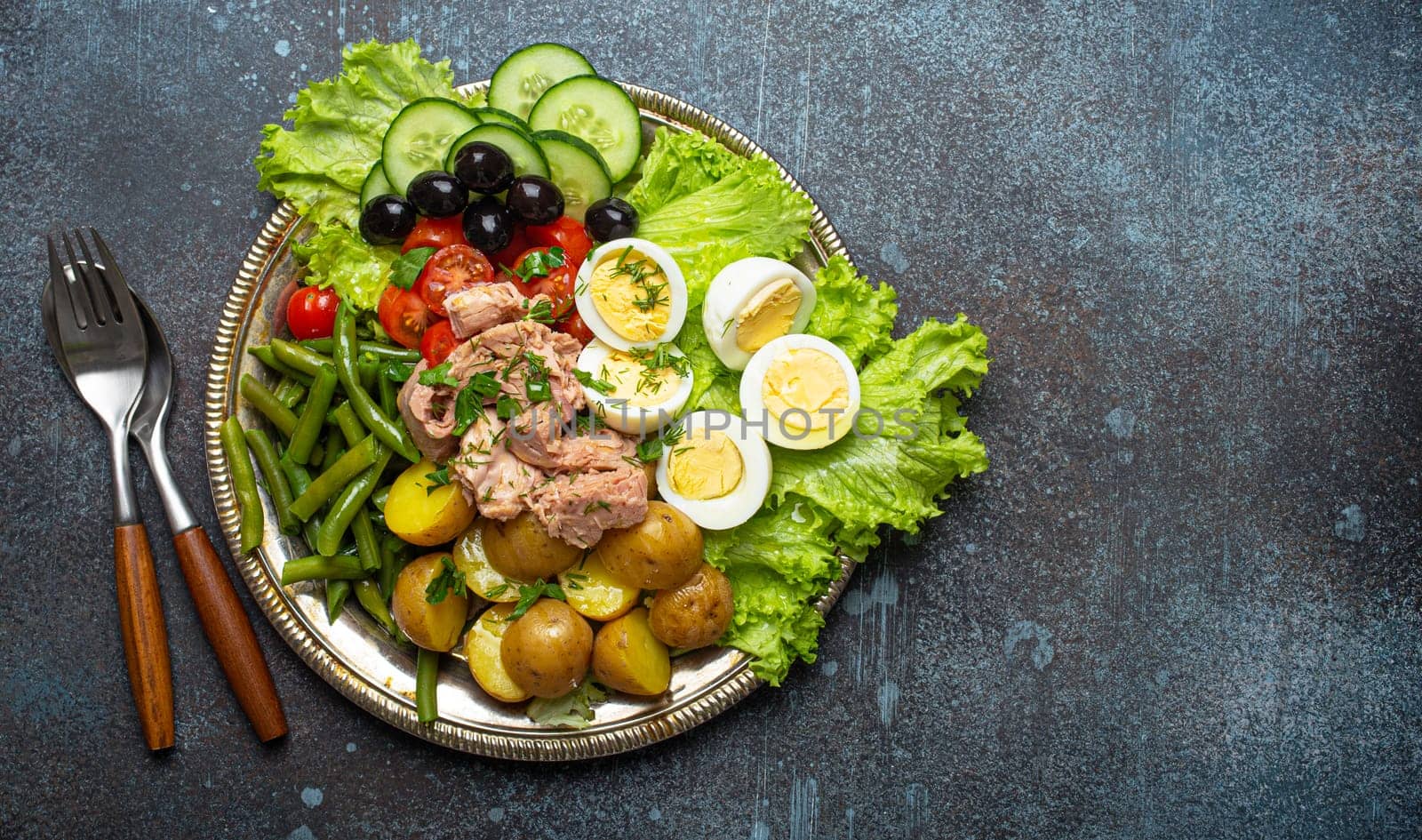 Nicoise salad with tuna, olives, green beans, tomatoes and quail eggs on a bed of lettuce with copy space by its_al_dente