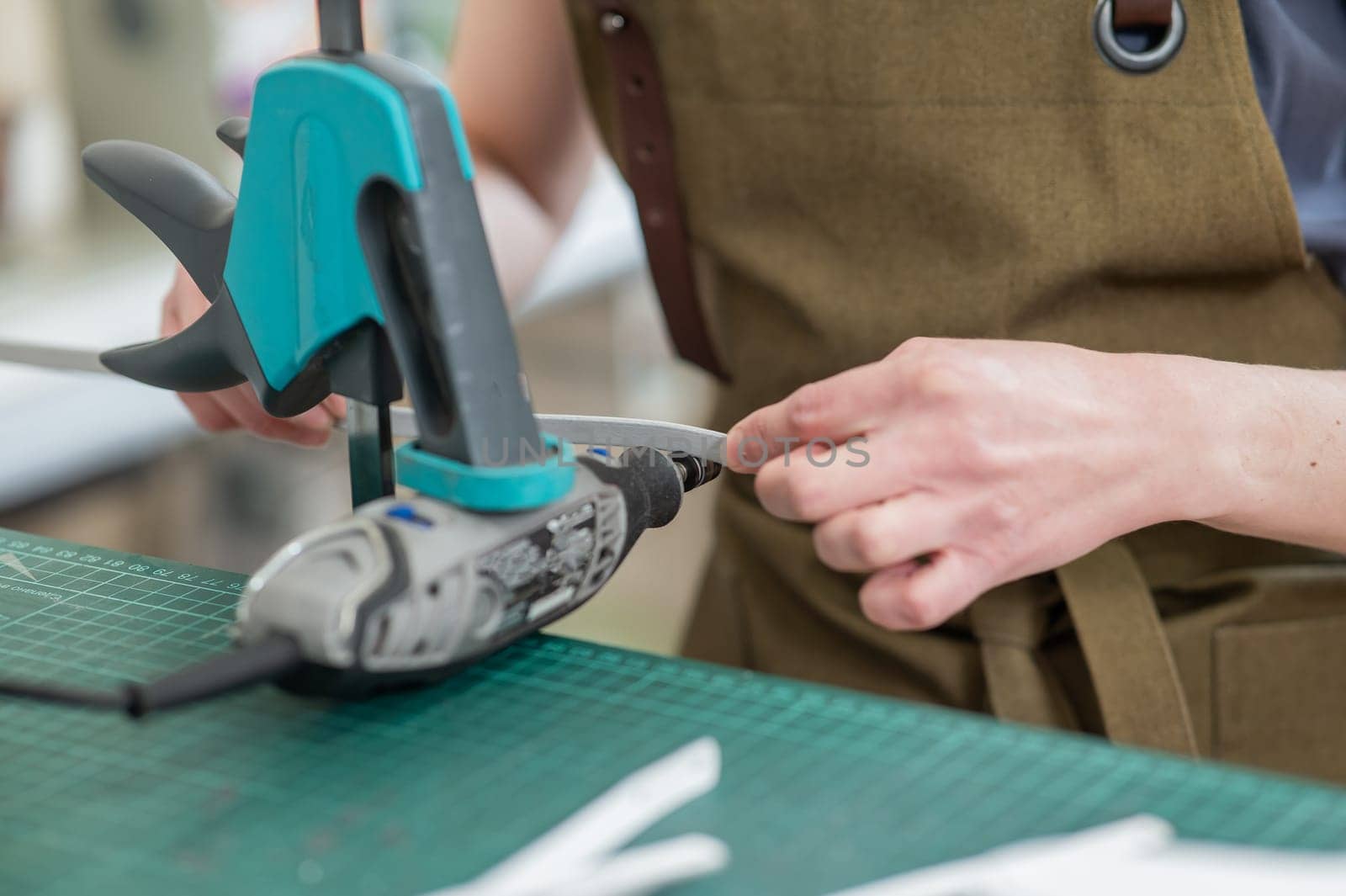 A tanner processes the edges of a leather belt in a workshop. Close-up of woman's hands