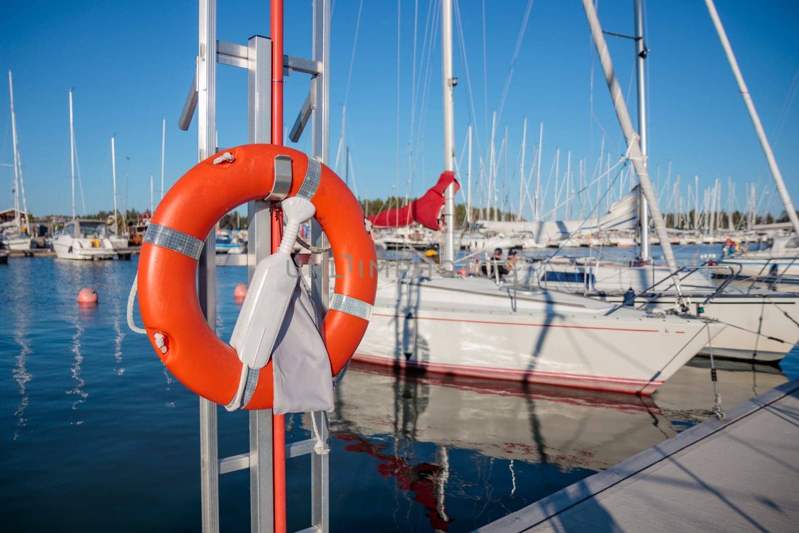 SOS nautical emergency concept. Lifebuoy, orange lifebelt put on vertical ready for using. Close up circle lifesaver buoy at Finnish marina