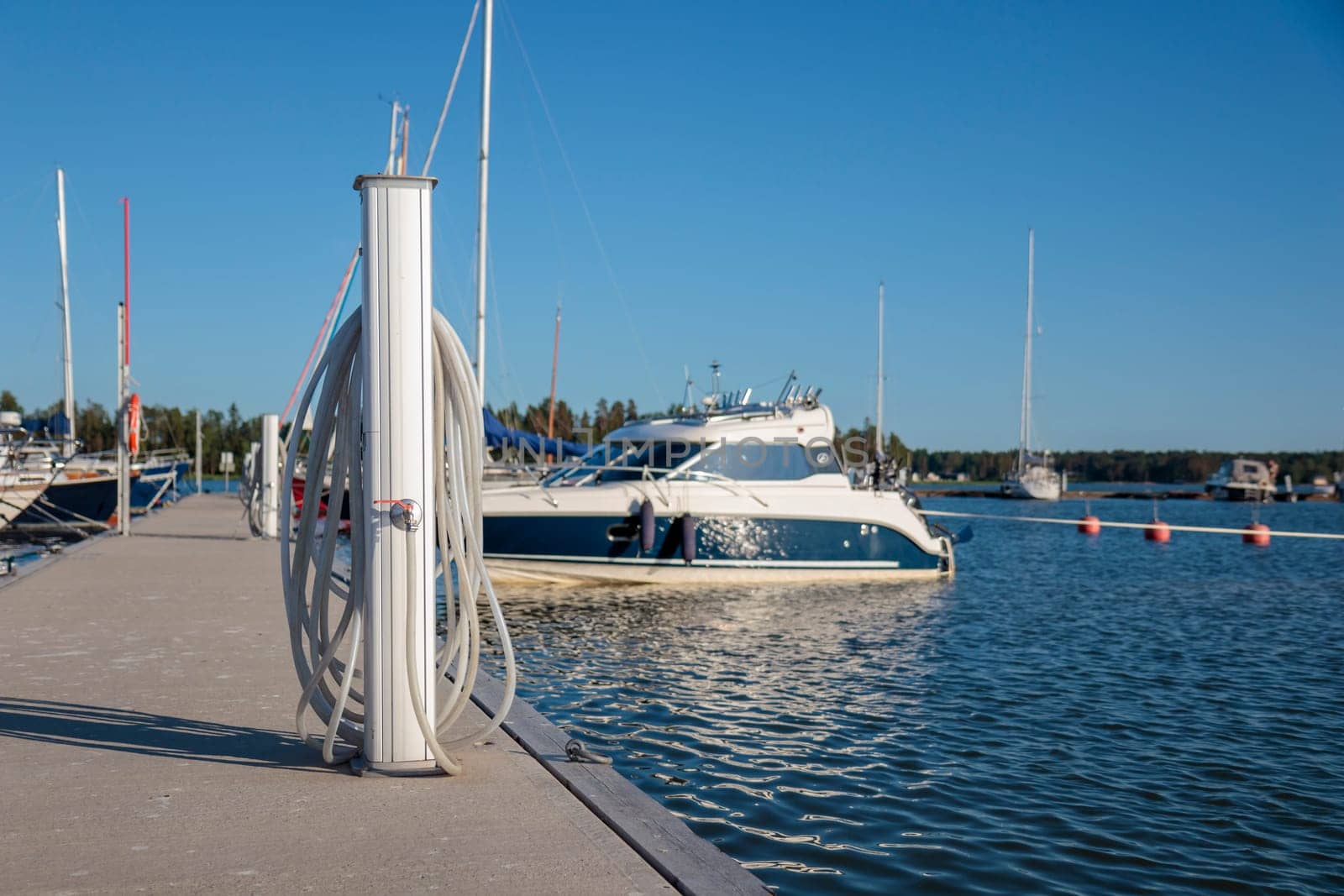 Charging and water station for boats, electrical outlets to charge ships in harbor, water vent and hose. Shore in marina jetty. Electrical power and drinking sweet water point on pier near sea coast. Yachts docked
