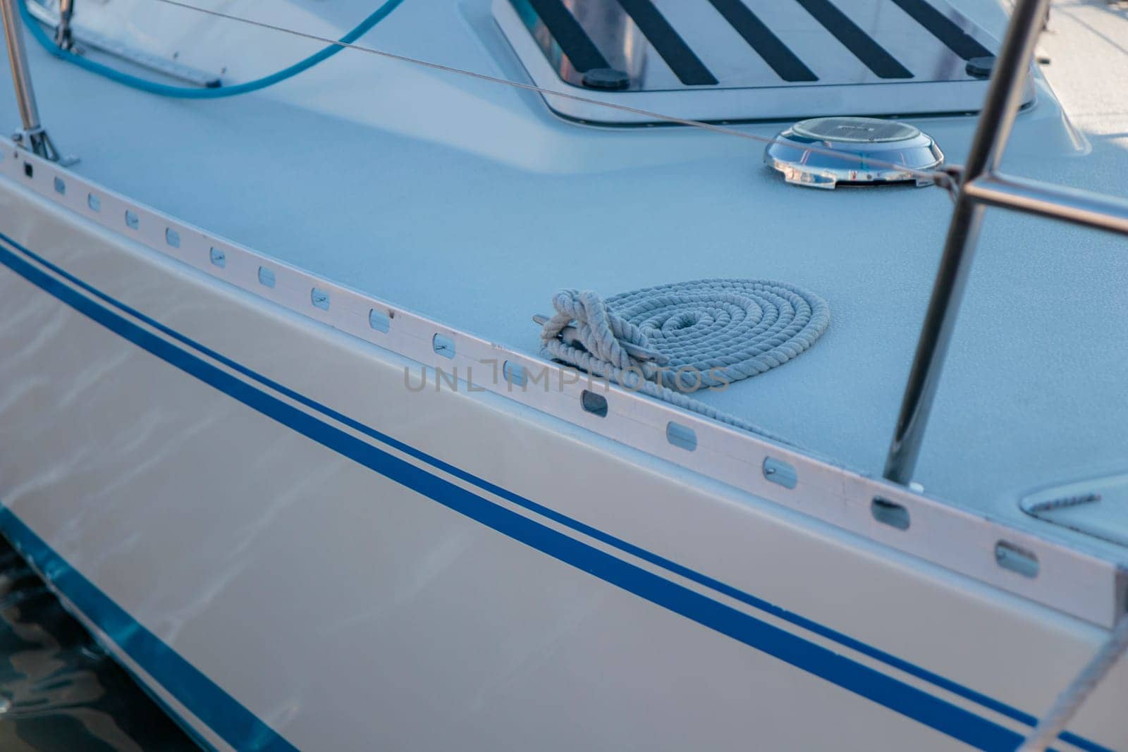 White rope tied to the mooring cleat of a sailboat, sunny light by Gudzar