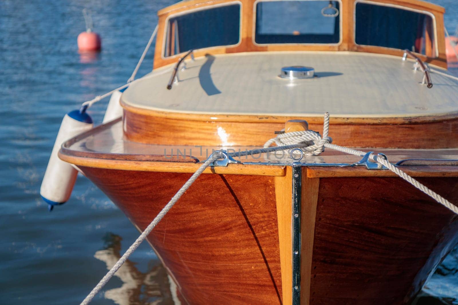 White rope tied to the mooring cleat of a wooden sailboat, sunny light, Finland