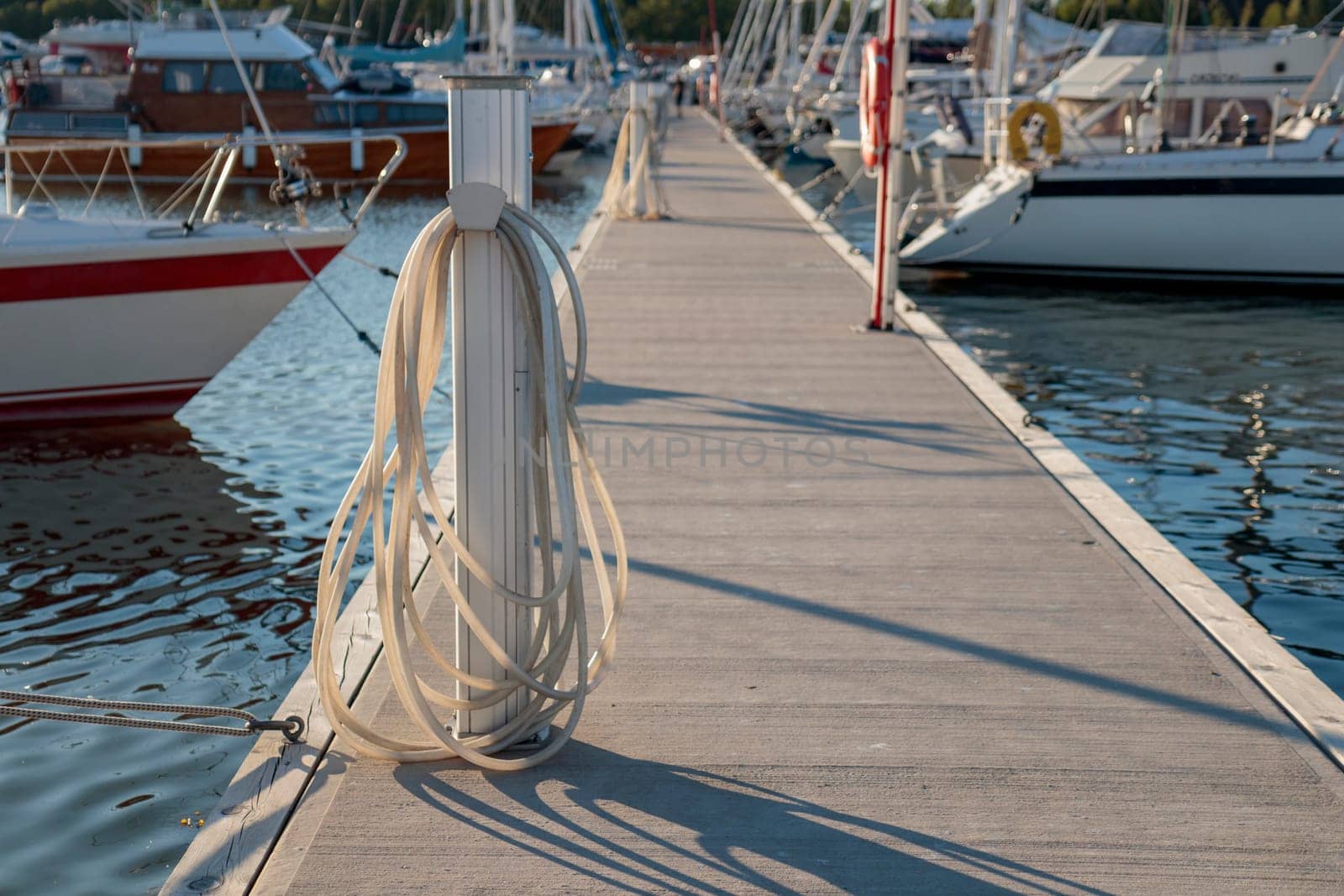 Charging and water station for boats, electrical outlets to charge ships in harbor, water vent and hose. Shore in marina jetty. Electrical power and drinking sweet water point on pier near sea coast. Yachts docked