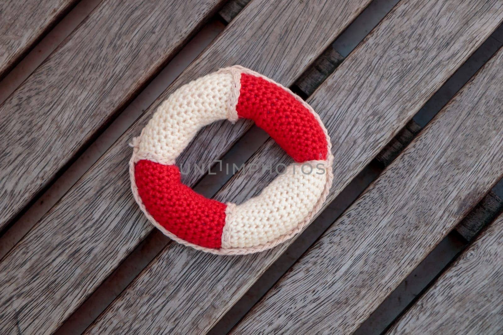 Handmade small crocheted toy lifebelt on the wood