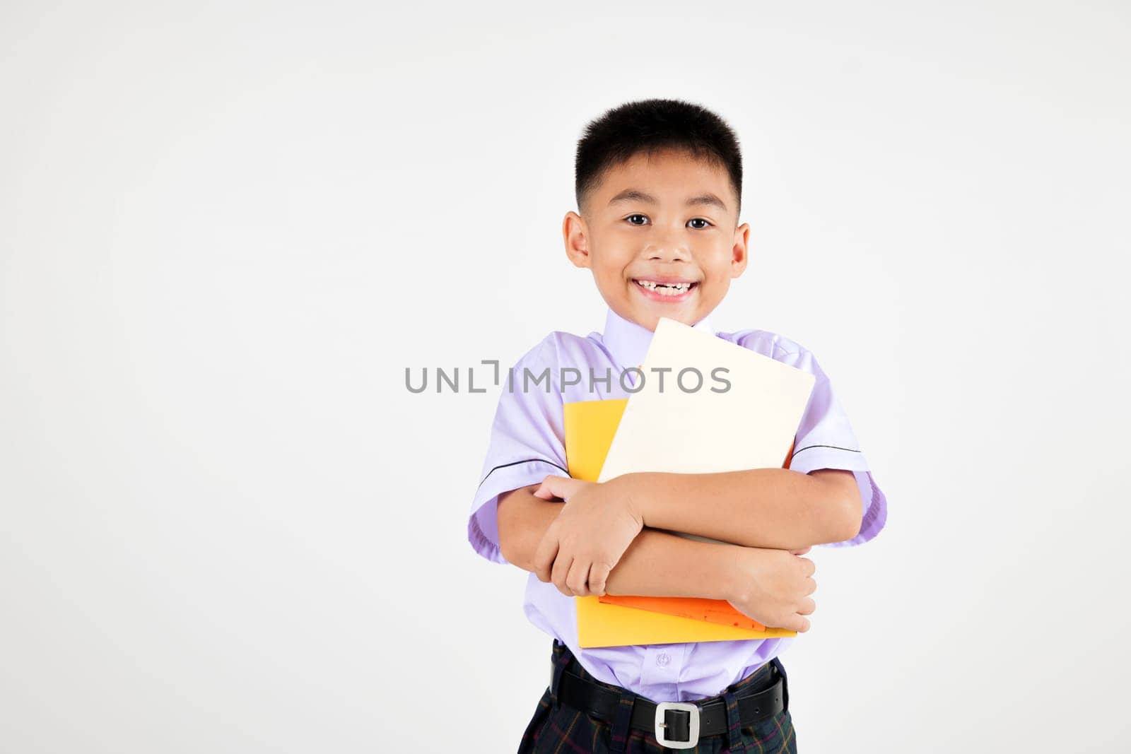 Portrait smile Asian little boy primary posing holding or hugging book studio shot isolated white background, happy cute man kid wear school uniform pride, back to school concept