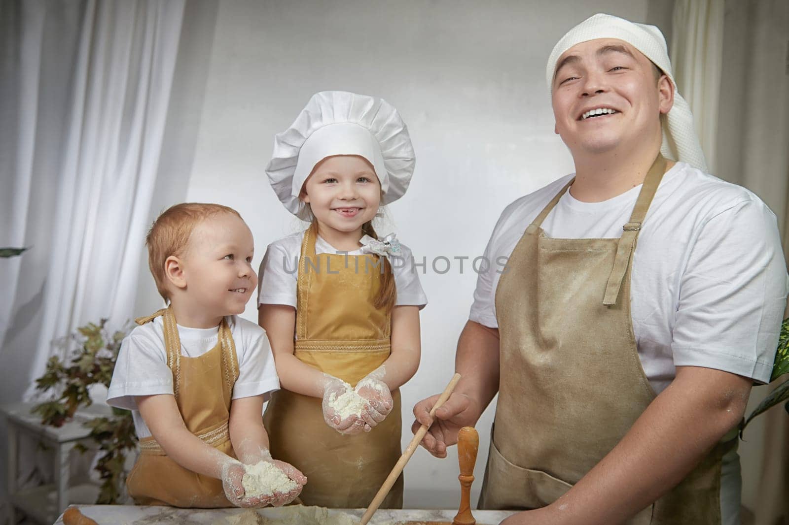 Cute oriental family with father, daughter, son cooking in the kitchen on Ramadan, Kurban-Bairam. Funny family at cook photo shoot. Easter by keleny