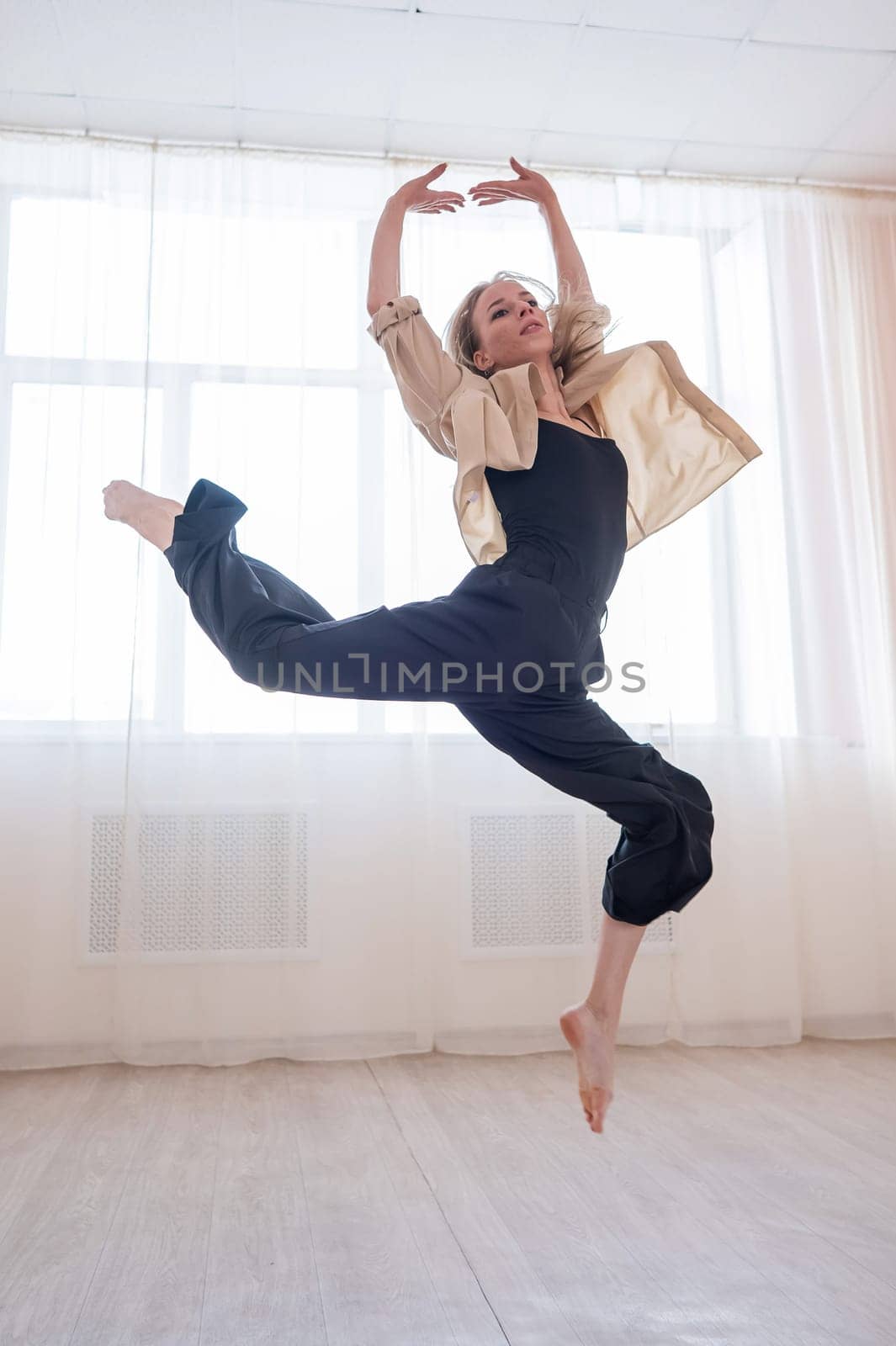 Caucasian woman dances contemporary in ballet class. Dancer in a jump. Vertical photo. by mrwed54