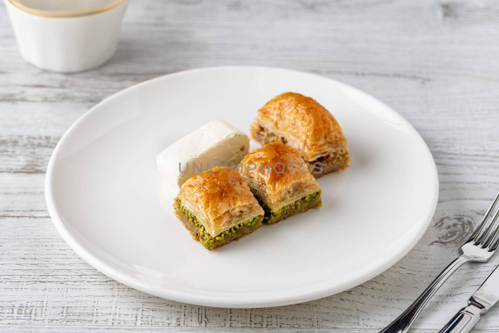 Traditional Turkish dessert pistachio baklava on a white porcelain plate