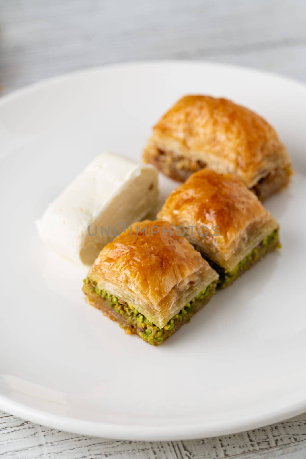 Traditional Turkish dessert pistachio baklava on a white porcelain plate