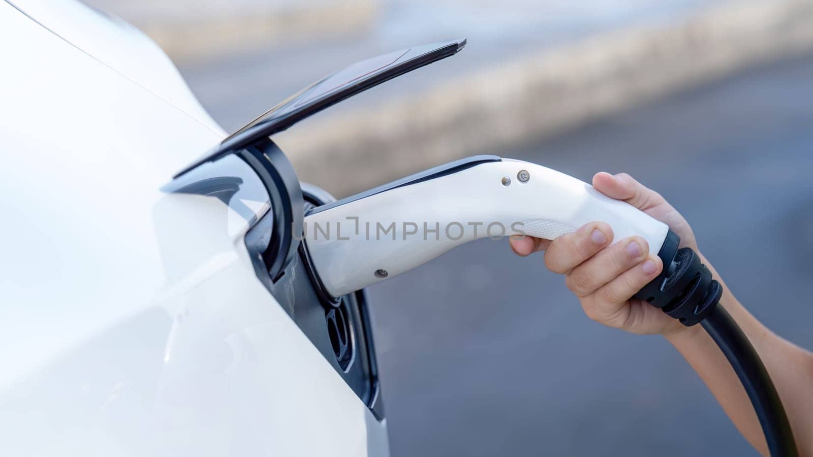 Hand insert EV charger plug into electric vehicle to recharge EV car. Perpetual by biancoblue