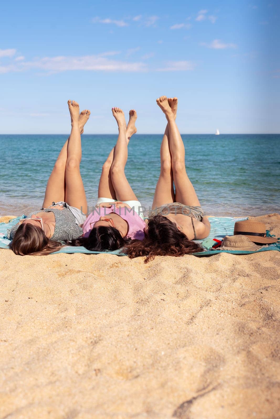 Vertical portrait three beautiful girls on the beach lying on the sand by mariaphoto3