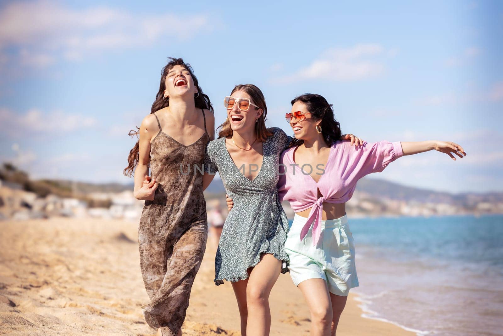 Cheerful multiethnic friends with sunglasses happy on vacation on the beach, looking at the camera.