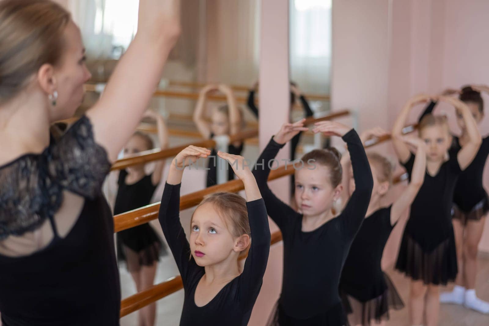 Children's ballet school. Caucasian woman teaching ballet to little girls
