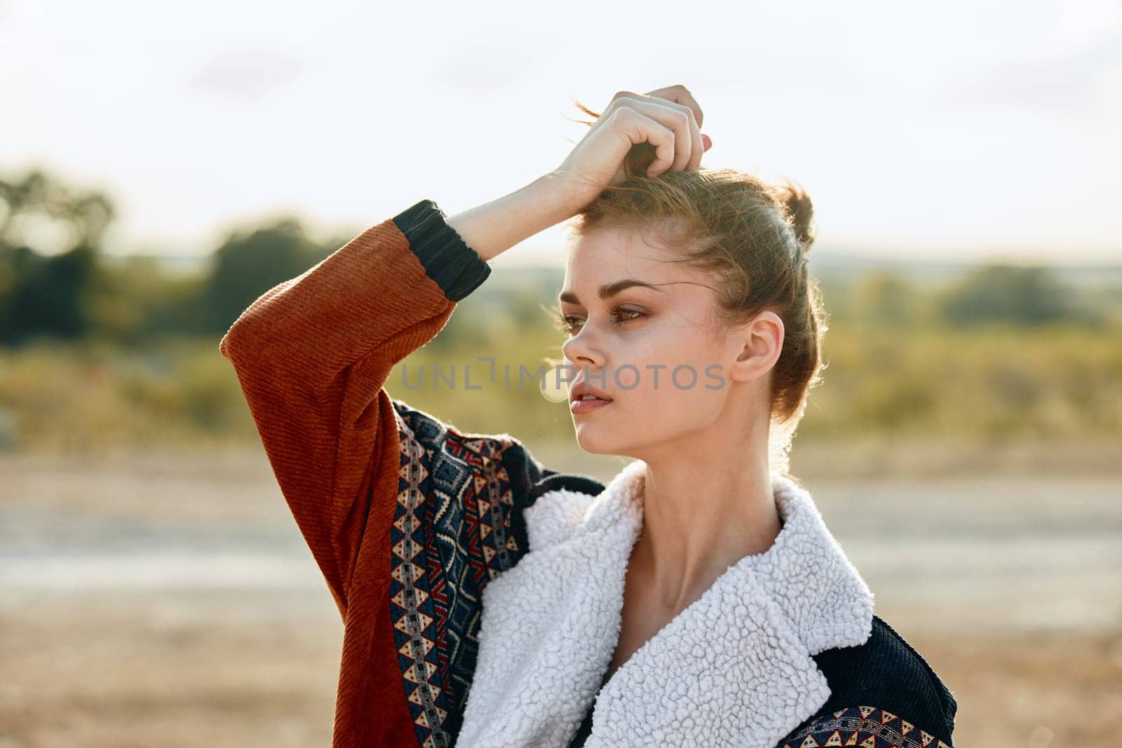 Stressed woman standing alone in vast field with hands on head in contemplation by Vichizh