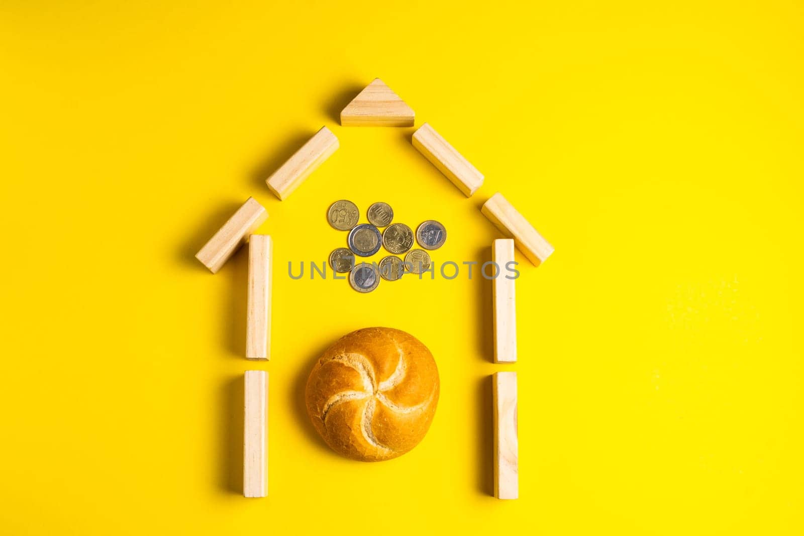 Hand holding money coins close to bread on a yellow background