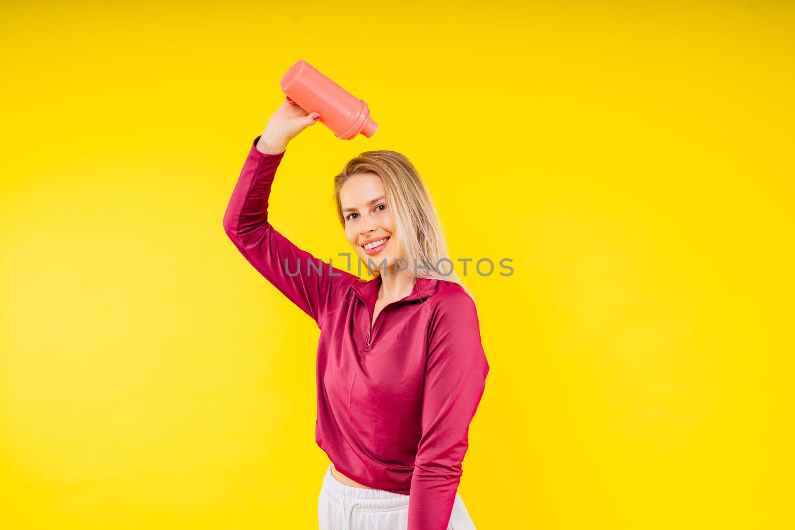 Studio fitness female portrait with bottle of water isolated on a yellow background