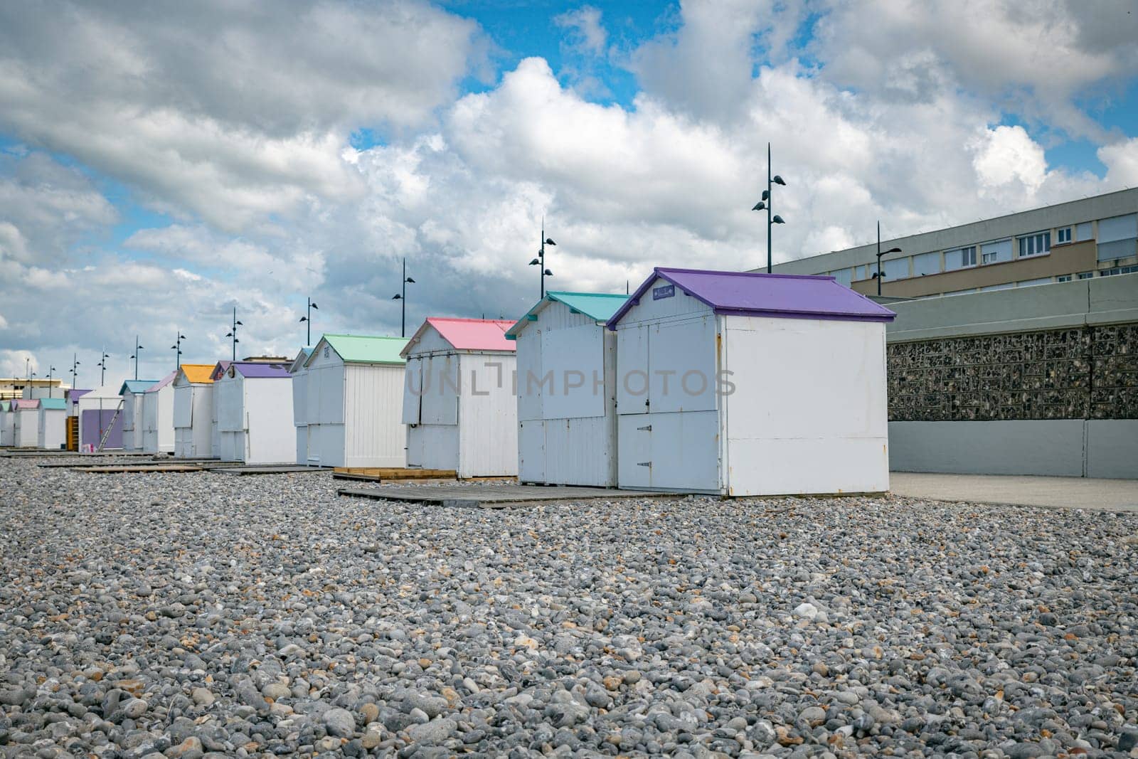 wooden beach houses with different colored roofs on the beach of le treport in France Normandy with a cloudy sky as a background