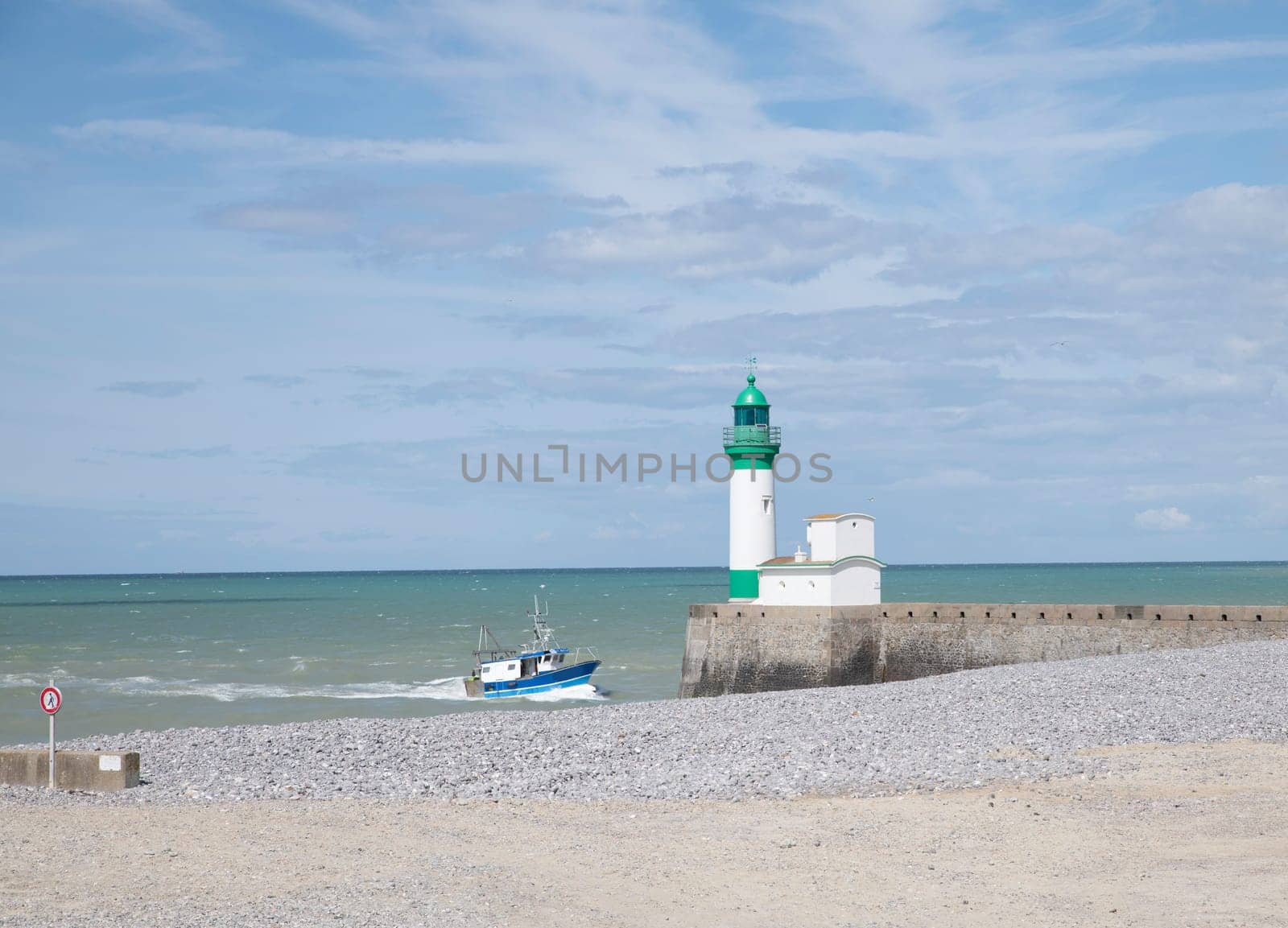 Le Treport lighthouse Seine Maritime, Normandy, France with the beach as foreground and and a fishing boat