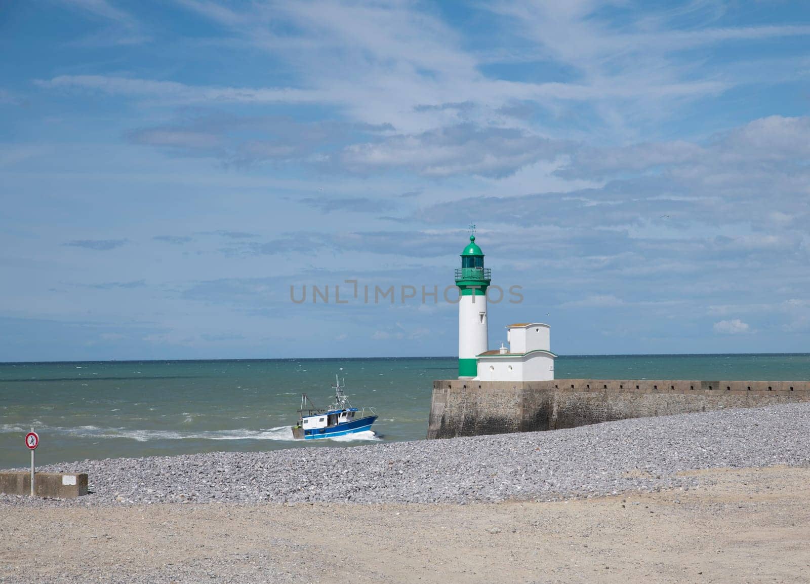 Le Treport lighthouse Seine Maritime, Normandy, France with the beach as foreground and and a fishing boat