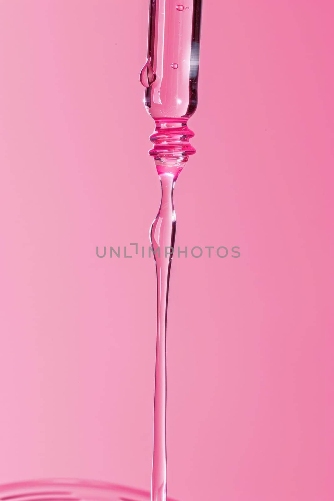 Pink liquid dripping from a syringe on a pink background for medical and health concept