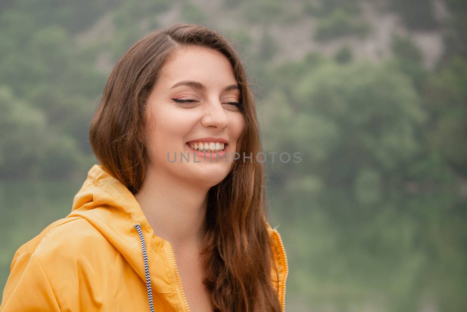 A woman in a yellow jacket is smiling and looking at the camera by Matiunina