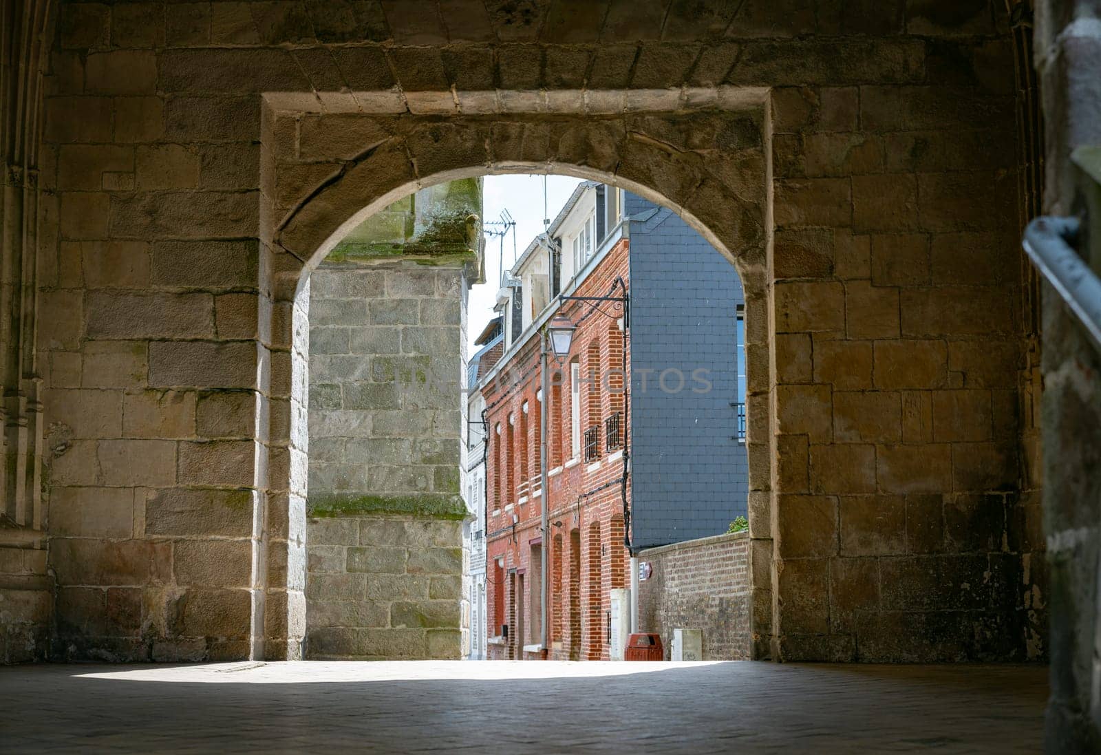 a view through an old church wall in a street in le treport in normandy in france