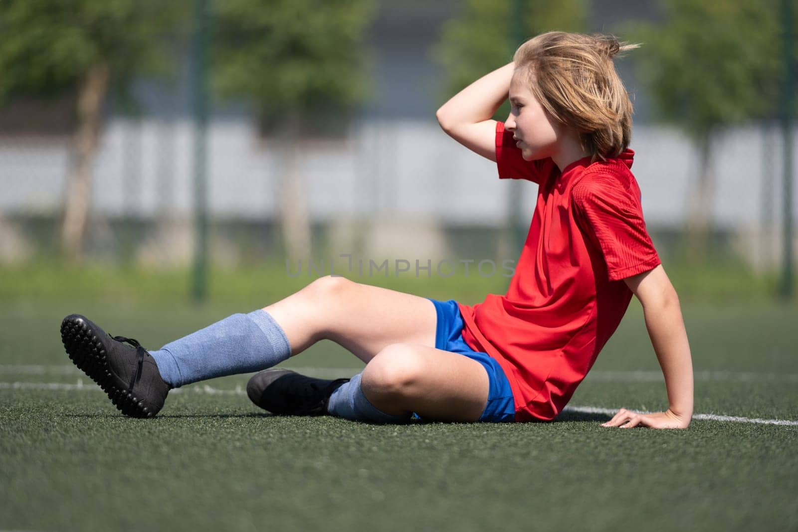 Girl In Football Uniform Sits At Match On Football Field