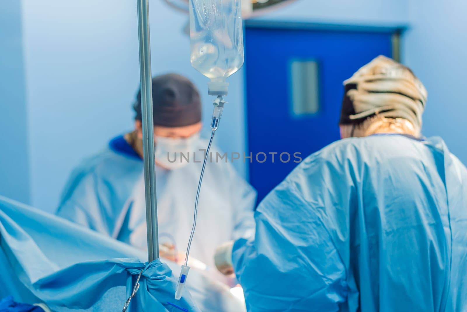 Shot In Operating Room of Two Surgeons During the Surgery Procedure Bending Over Patient with Instruments. Professional Doctors in Modern Hospital