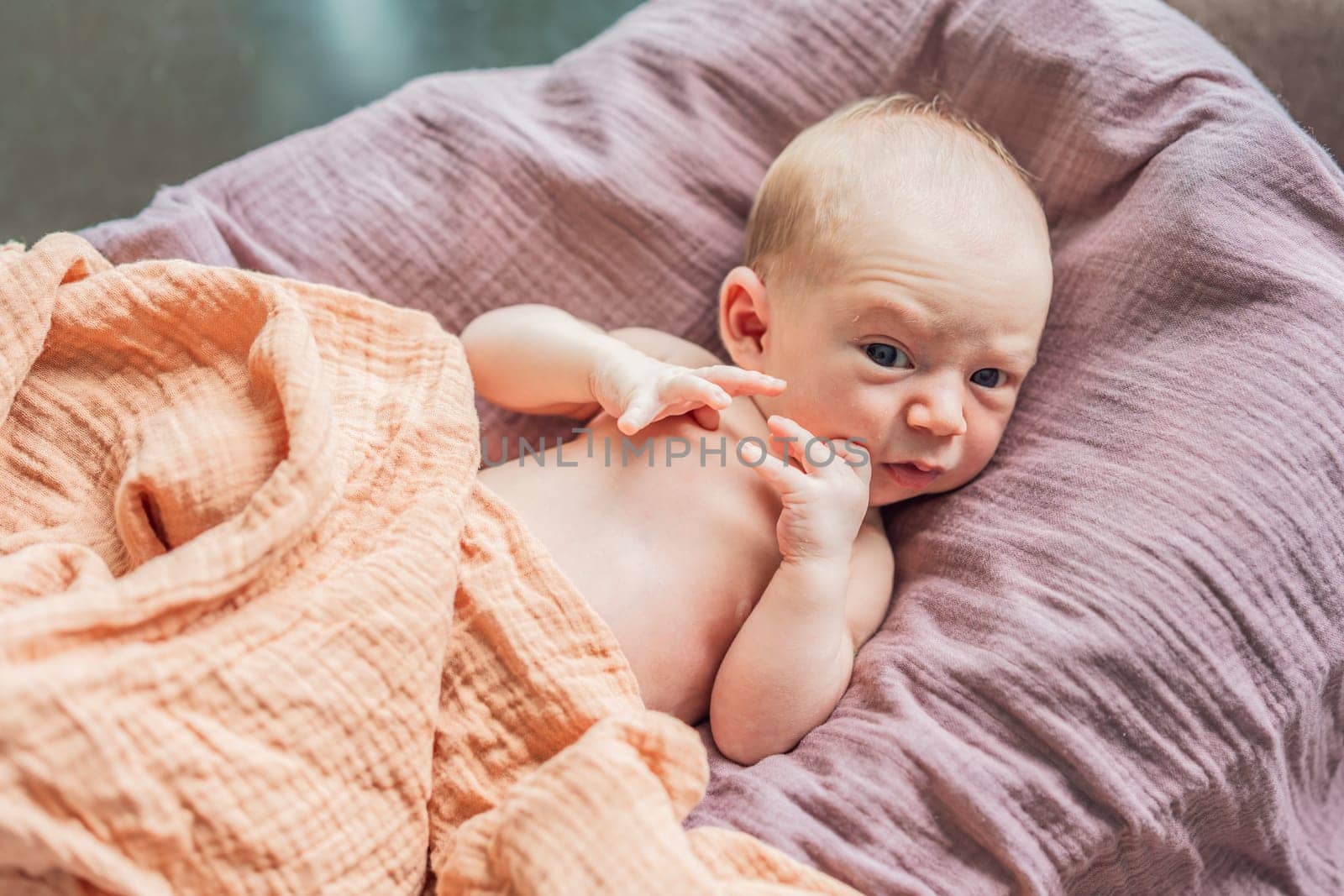 A newborn lies in his cozy cocoon on muslin swaddles. This serene moment captures the comfort and security of a newborn, highlighting the gentle care and nurturing environment.