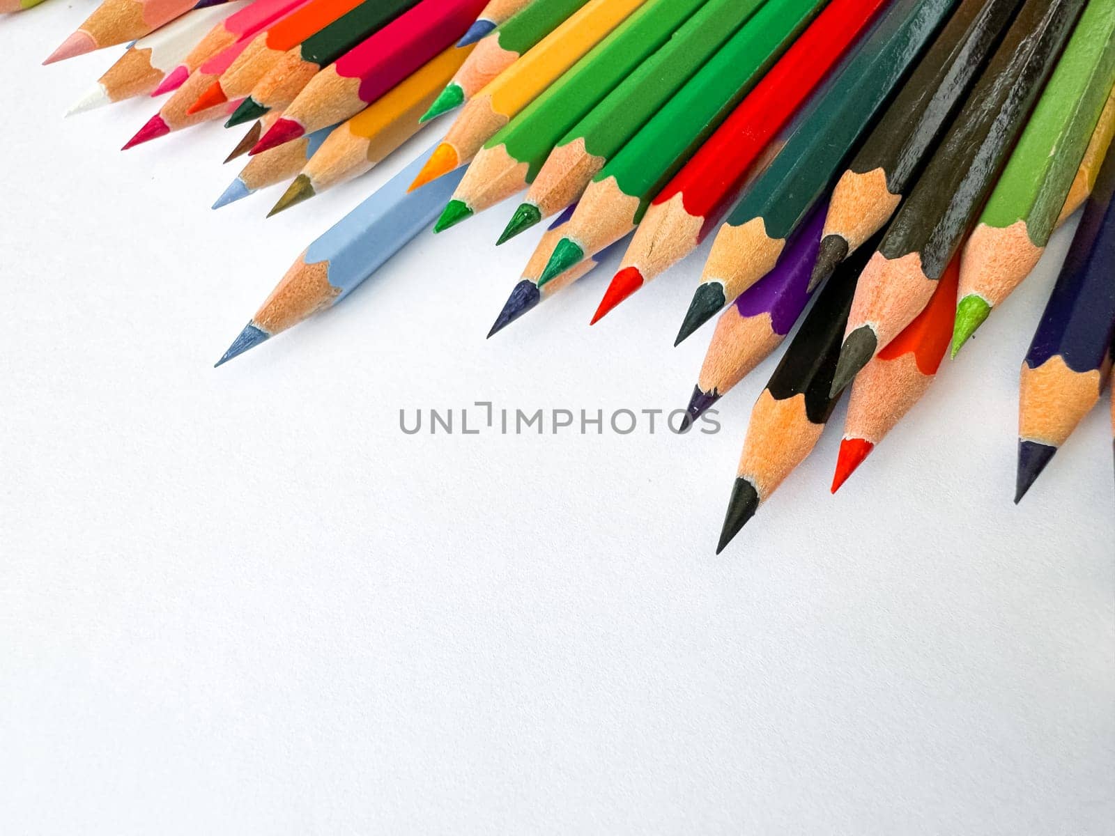 Diagonal arrangement of sharp multi colored pencils on white background with empty space for text. Artistic concept for stationery, education, design or advertising banner for school products.