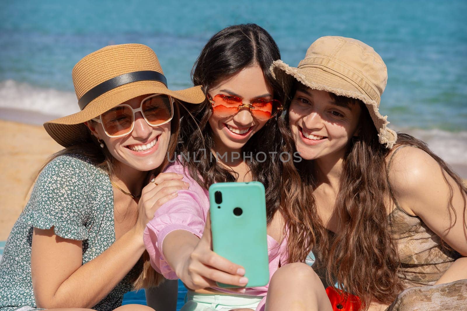 Group of smiling multiethnic women enjoying vacation. Beautiful and cheerful girls of generation z pose for a photo with a mobile phone.