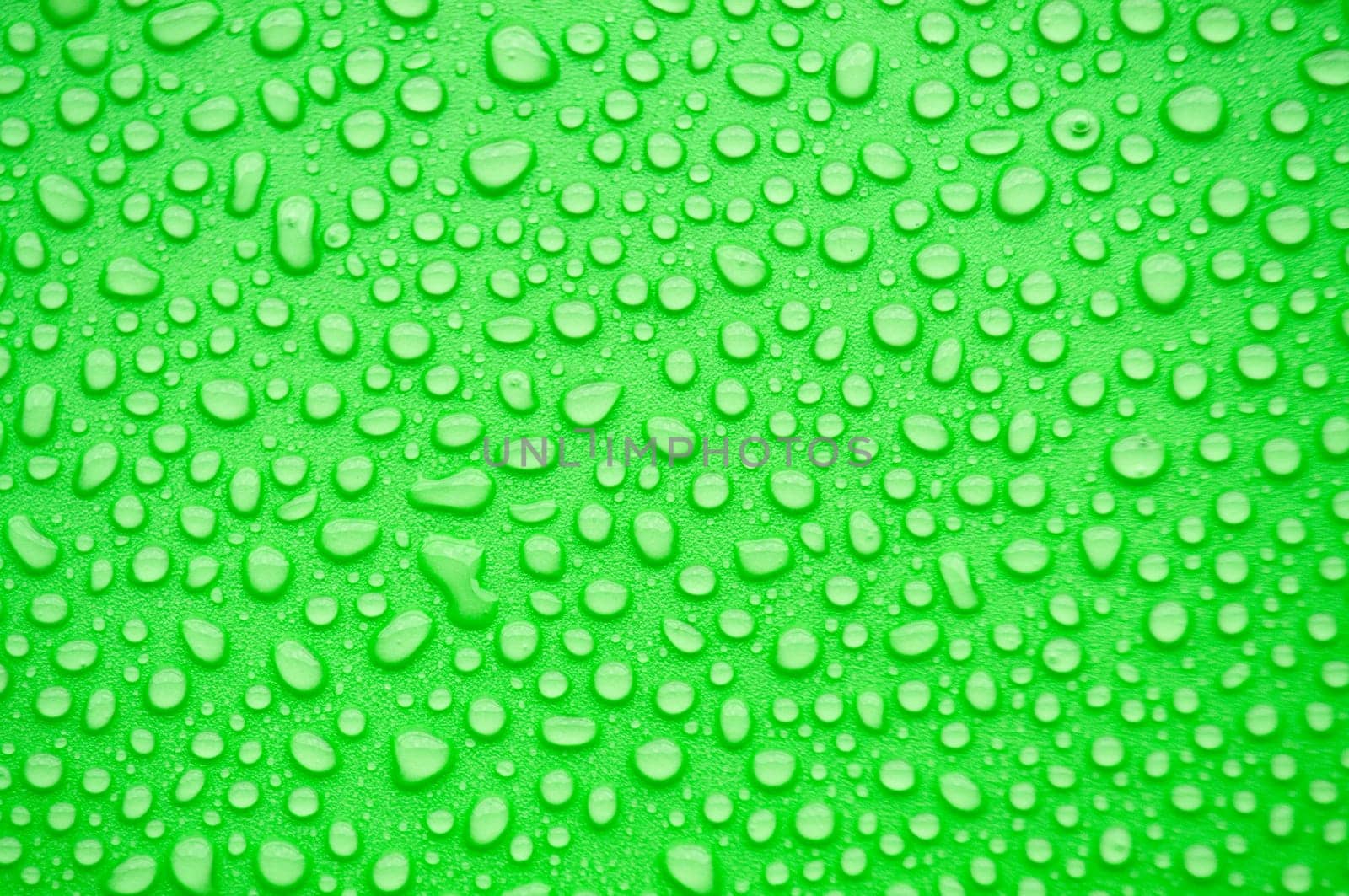 Top view of water droplets on green background.