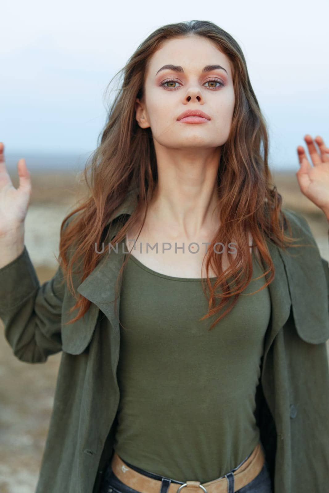 Woman celebrating with arms raised in desert landscape under a clear blue sky