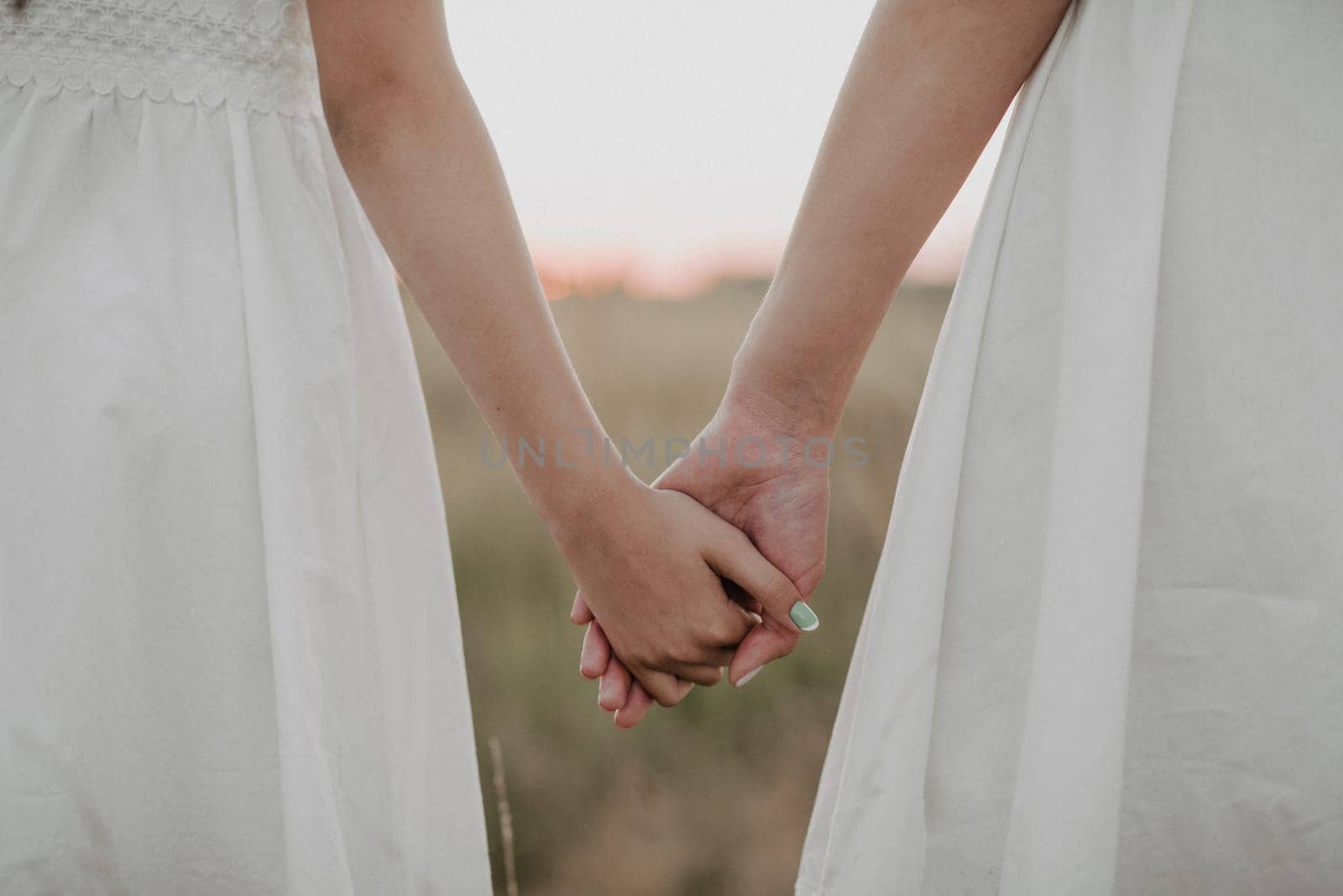 two girls holding hands together in the summer outdoors. Unity and family happiness. Added a small grain simulation of film photography